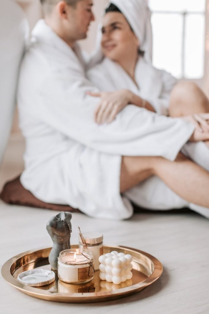 scented-candles-on-metal-tray-6634897 Cozy spa scene with couple embracing and aromatherapy candles creating a serene atmosphere.