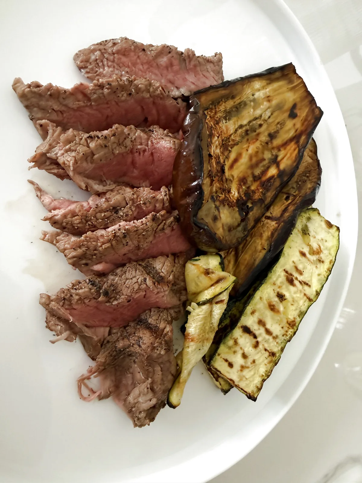 goveji steak s pečenimi bučkami in zeliščnim jogurtom na krožniku